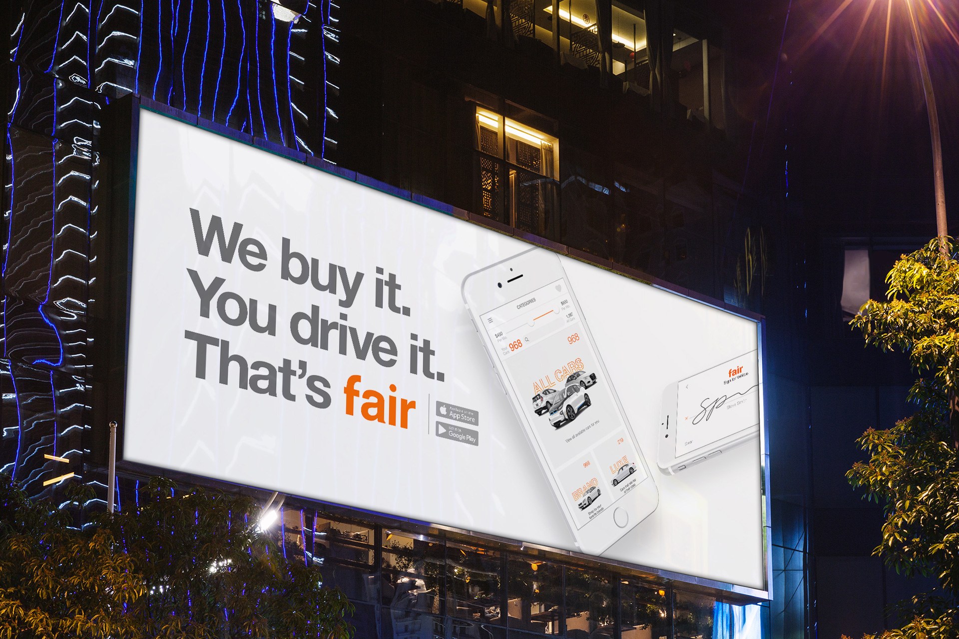 A Fair billboard at night: &lsquo;We buy it. You drive it. That's fair,&rsquo; with the app on screen
